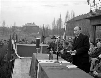 Budapest, 1957. március 29.: „Megvédjük a proletárdiktatúrát – Tízezrek vettek részt a fővárosban a párt forróhangulatú munkásgyűlésein. Biszku Béla, az MSZMP Intézőbizottságának tagja, belügyminiszter a X. kerületben, a Halom utcai sporttelepen mondott beszédet.” 