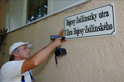 Egy munkás szlovák és magyar nyelvű utcanévtáblát helyez el Tótkomlóson